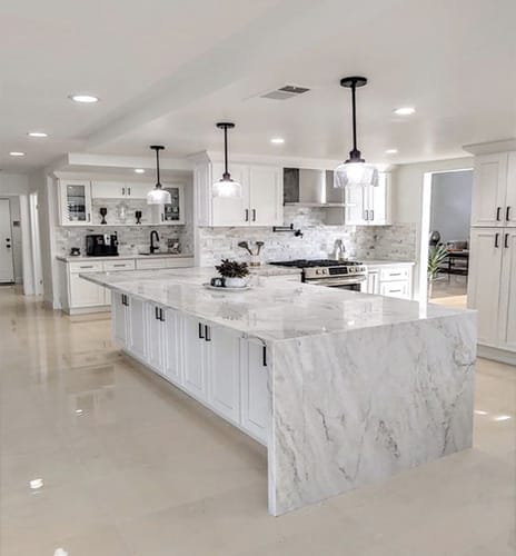 Wide view of a kitchen remodeled with a new island, flooring and backsplash