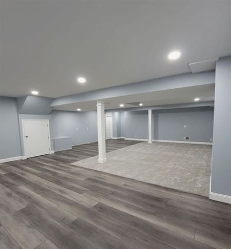 Wide view of a basement opened up with space and new wooden flooring installed